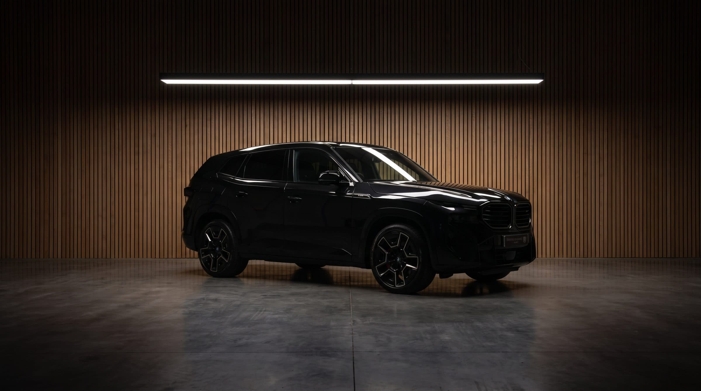 A black BMW XM under a single strip light